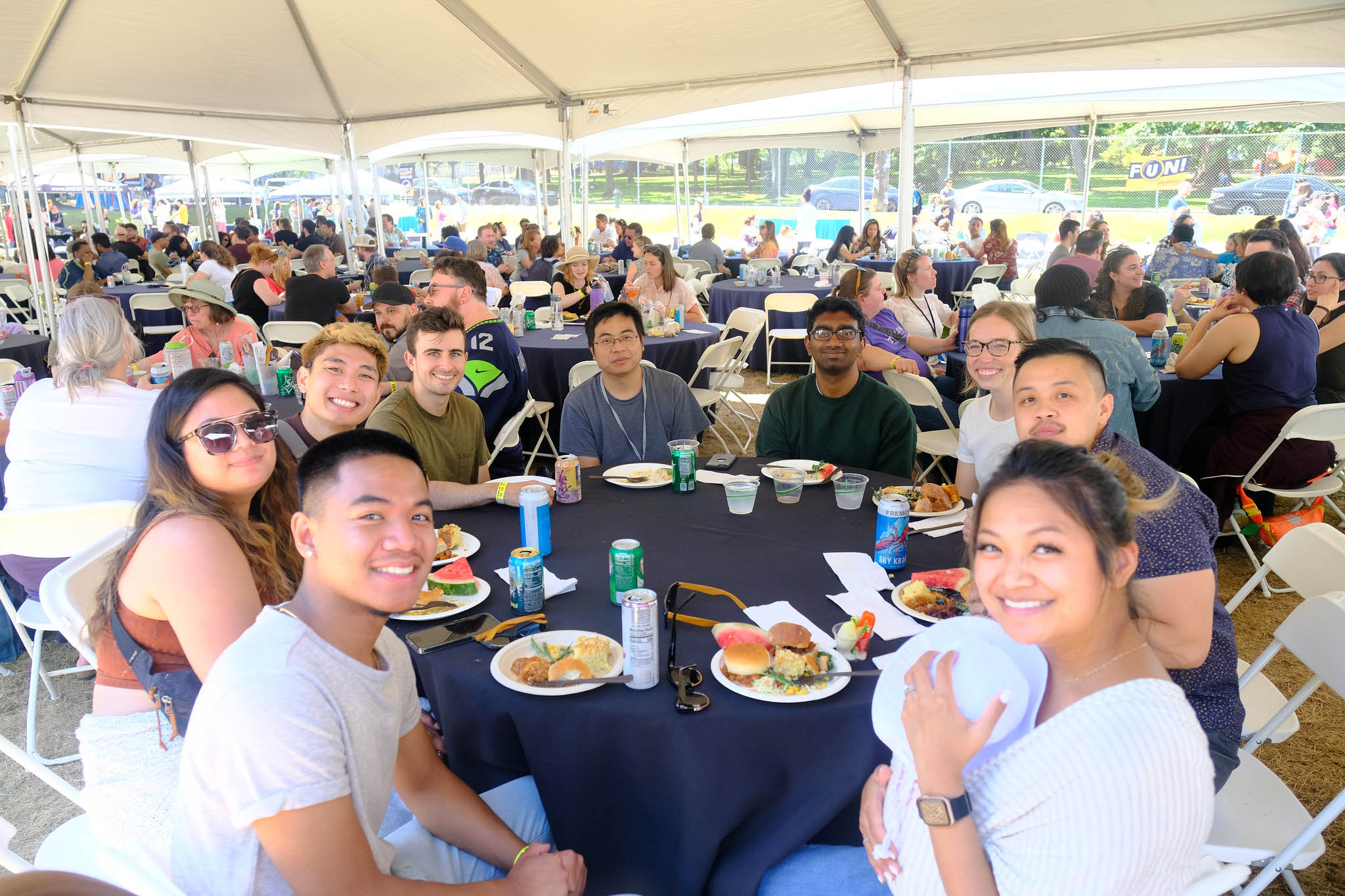 Allen institute staff seated at tables underneath a tent at a summer BBQ