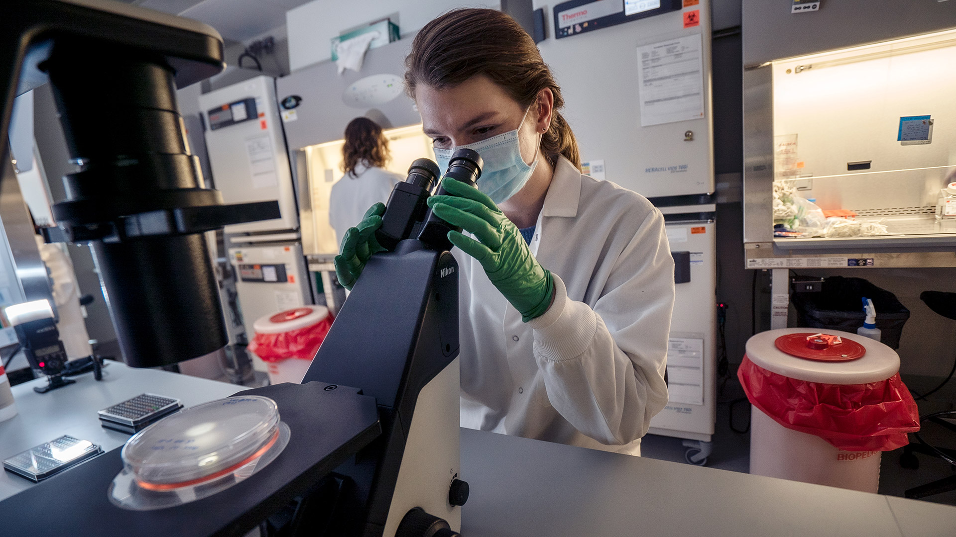 Female researcher in a lab viewing a sample through a microscope on a table