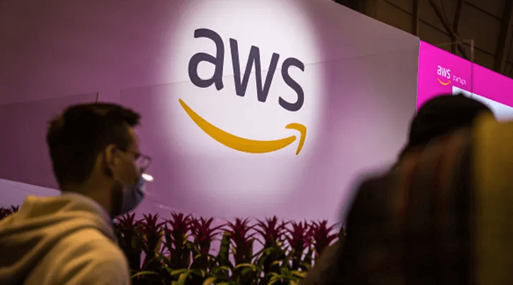 AWS (Amazon) logo against a purple backdrop with people in the foreground