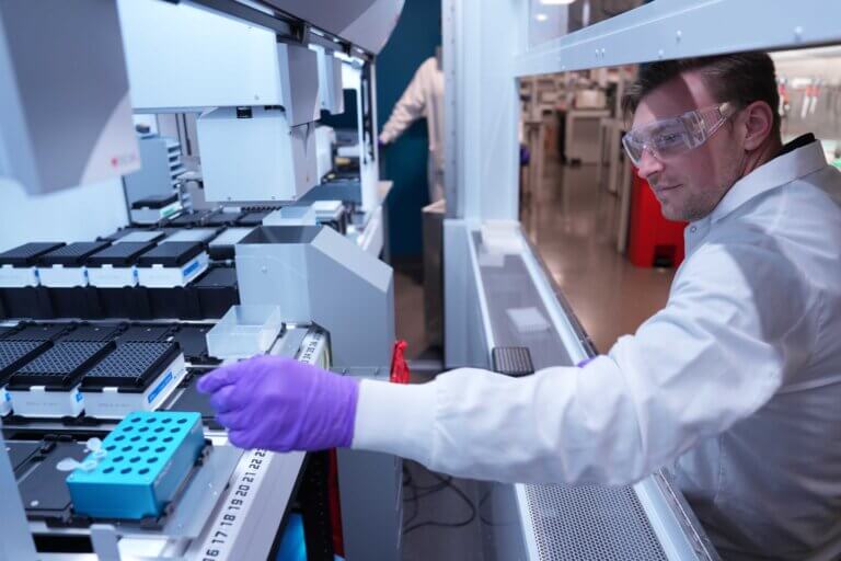Male researcher in a lab operating a blood sampling machine