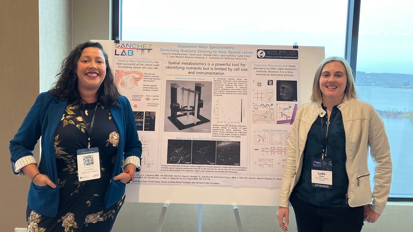 2 female scientists stand in front of poster