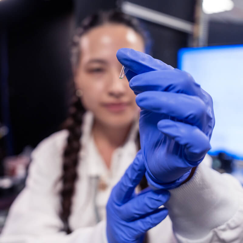 researcher in the lab holding up science equipment to the camera