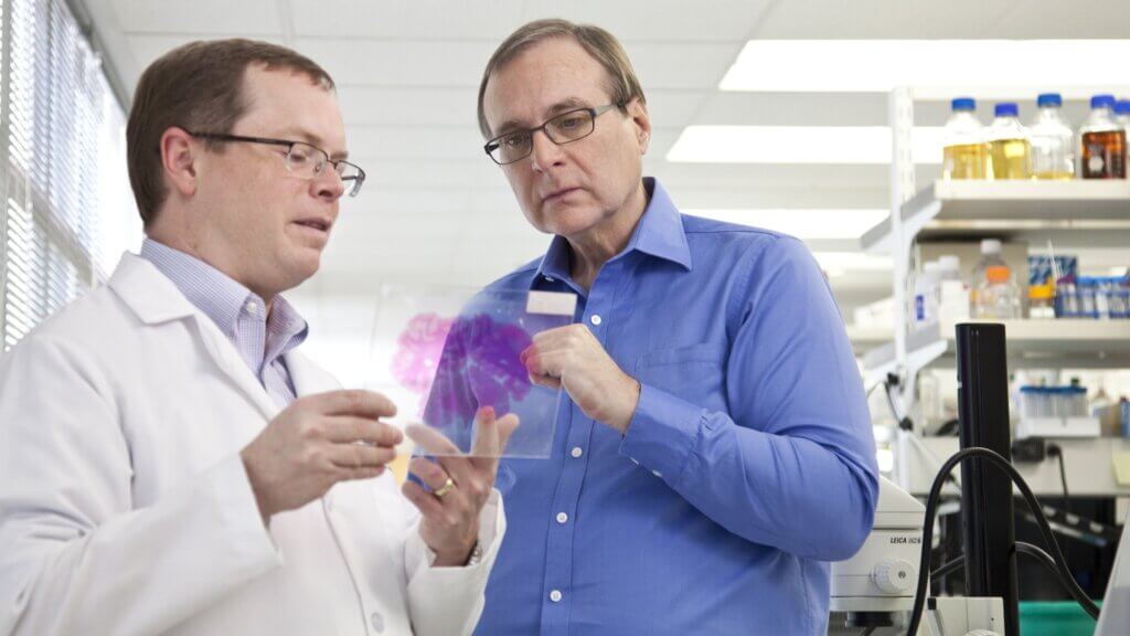 Allan Jones and Paul G. Allen in the lab at Allen Institute looking at a human brain section on a slide.