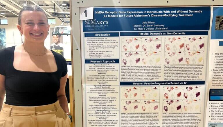 A neuroscience student standing next to her science poster