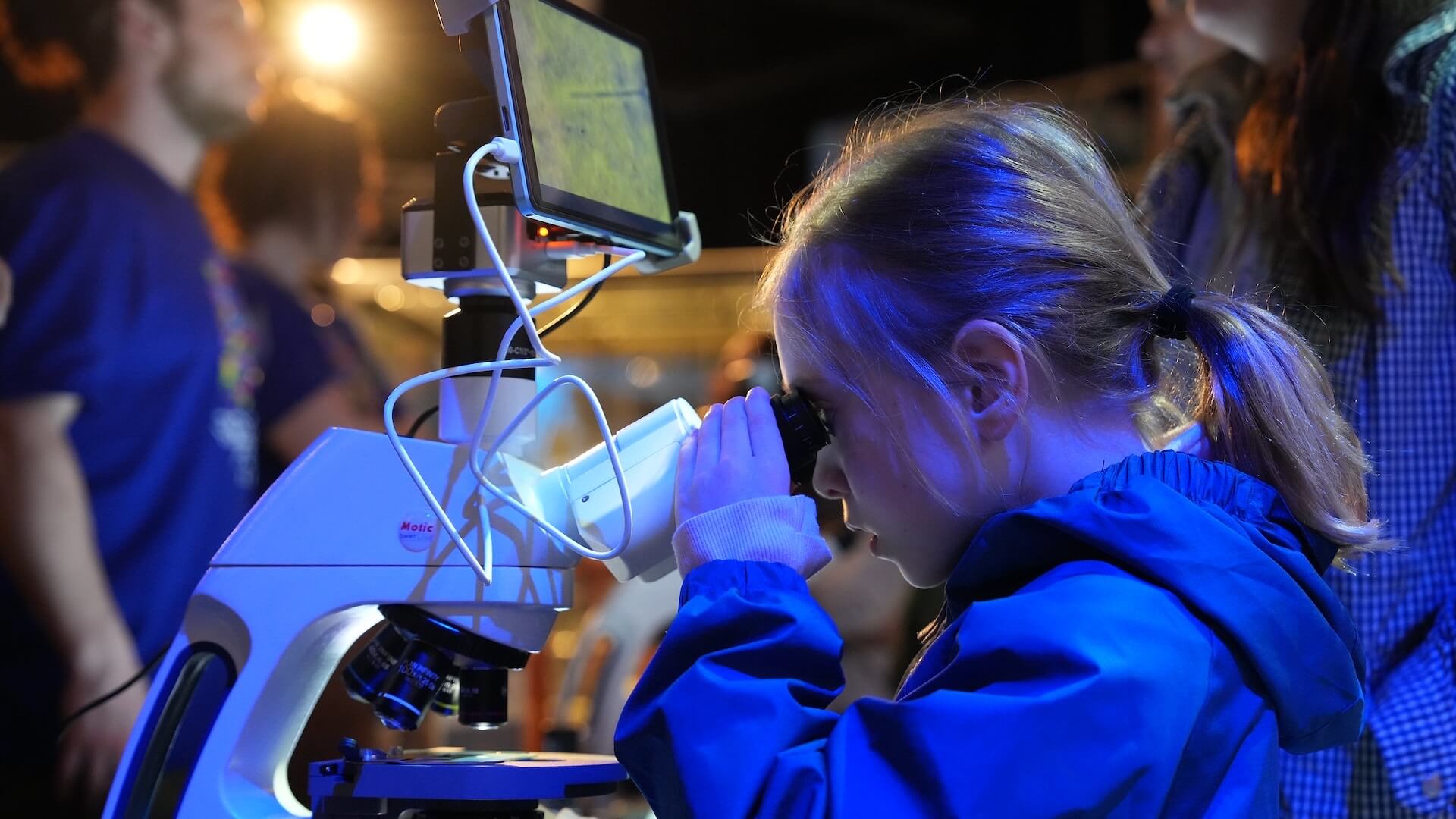 Kid looks through microscope at Brain Fest