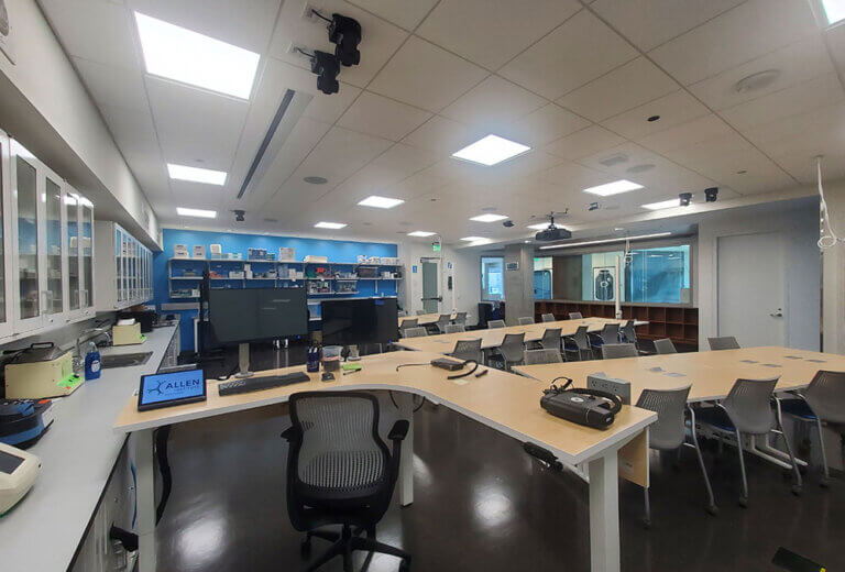 Lab tables with computer monitors and chairs
