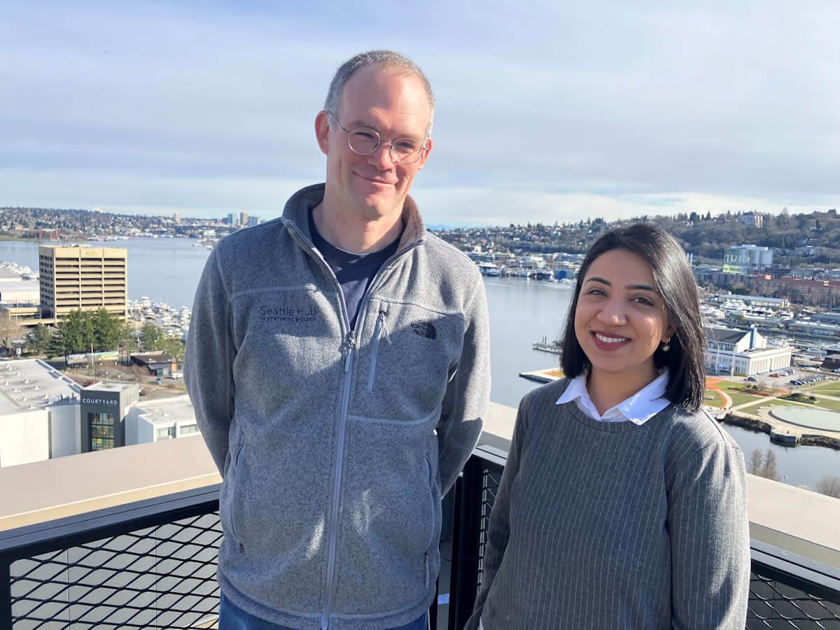 A male and female scientist stand in front of South Lake Union in Seattle.