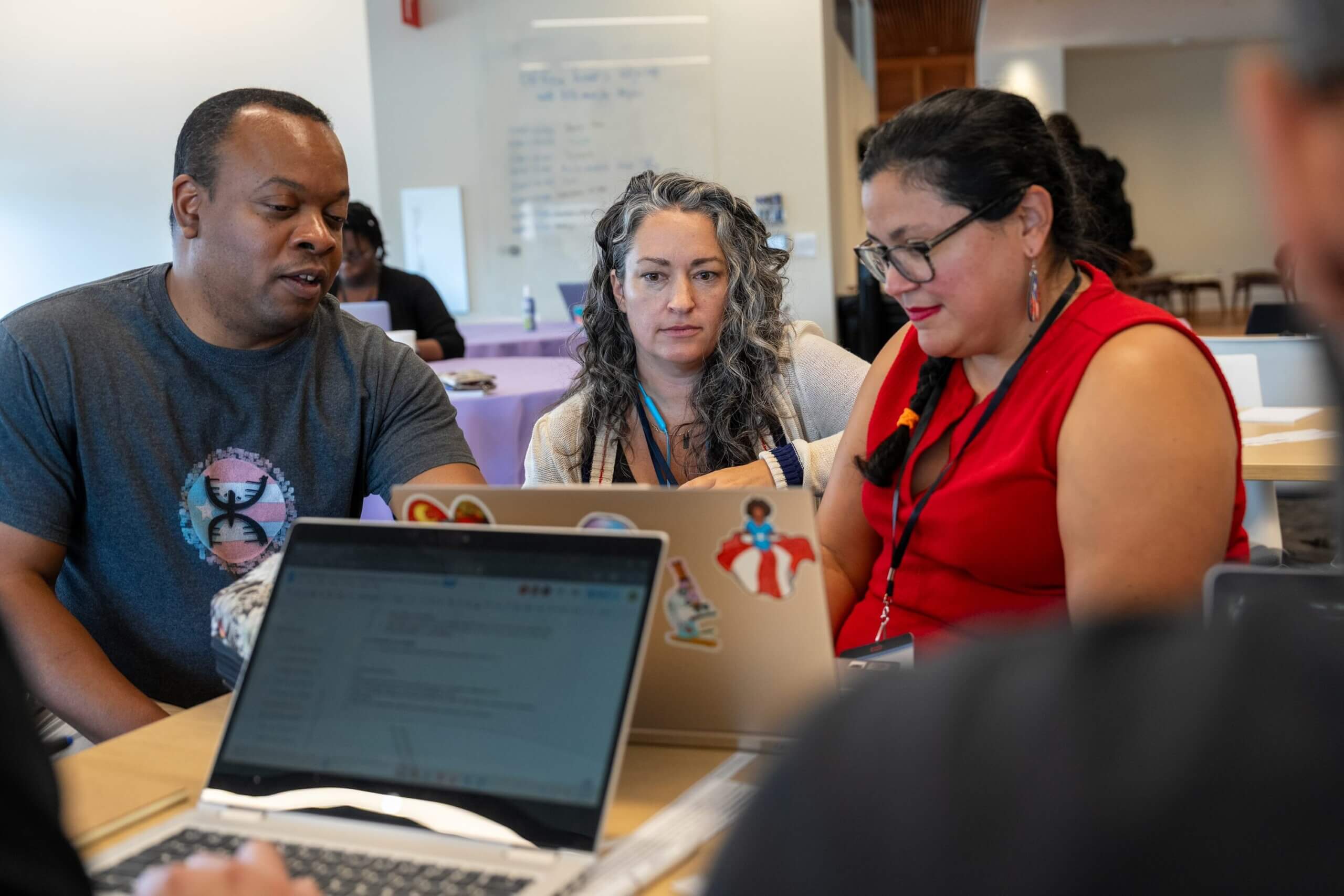 Three people sitting around a computer working