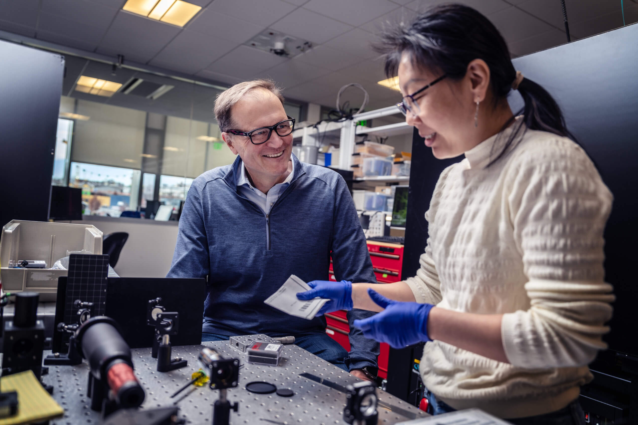 Karel Svoboda in a laboratory at the Allen Institute speaking with an Asian, female researcher