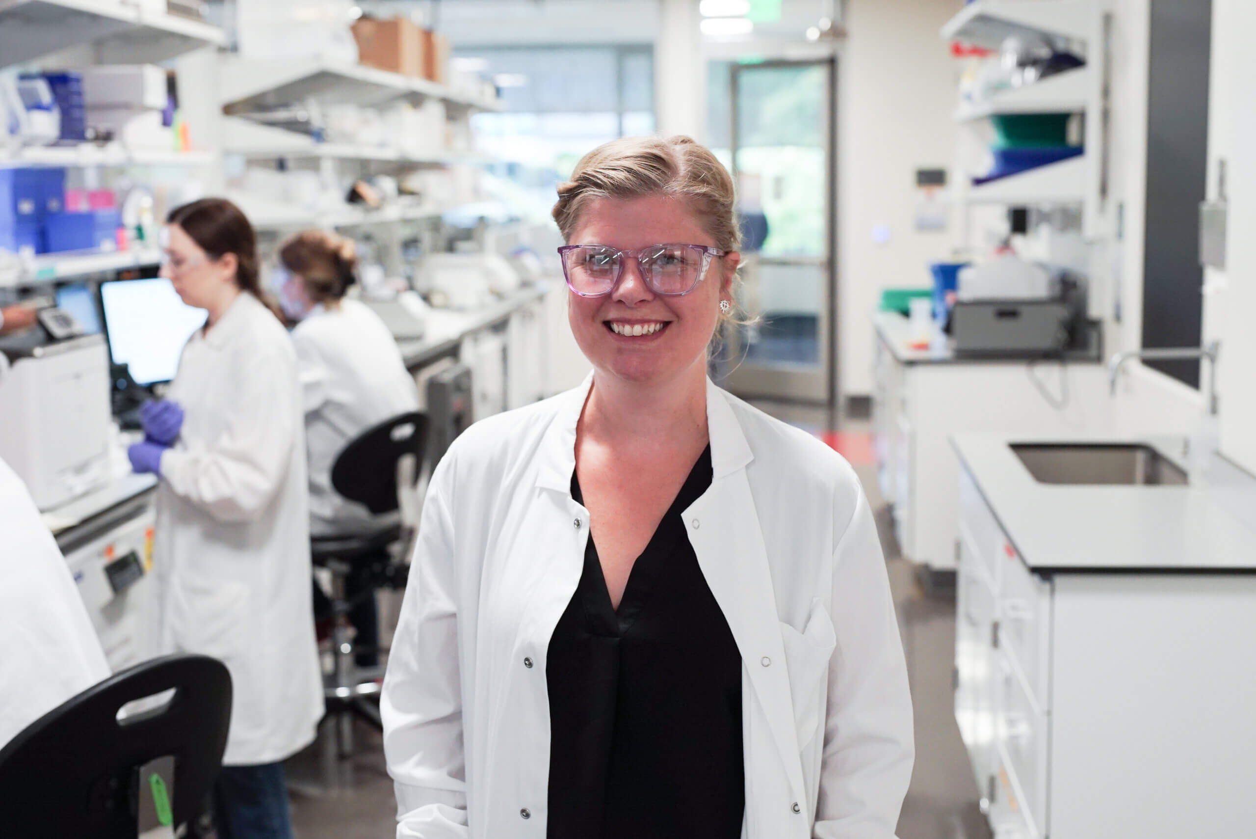 A female researcher wearing a white lab coat standing for a photo